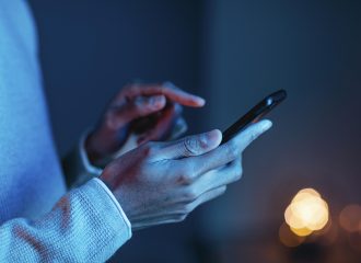 Mão de pessoa negra segurando um celular, olhando aplicativos